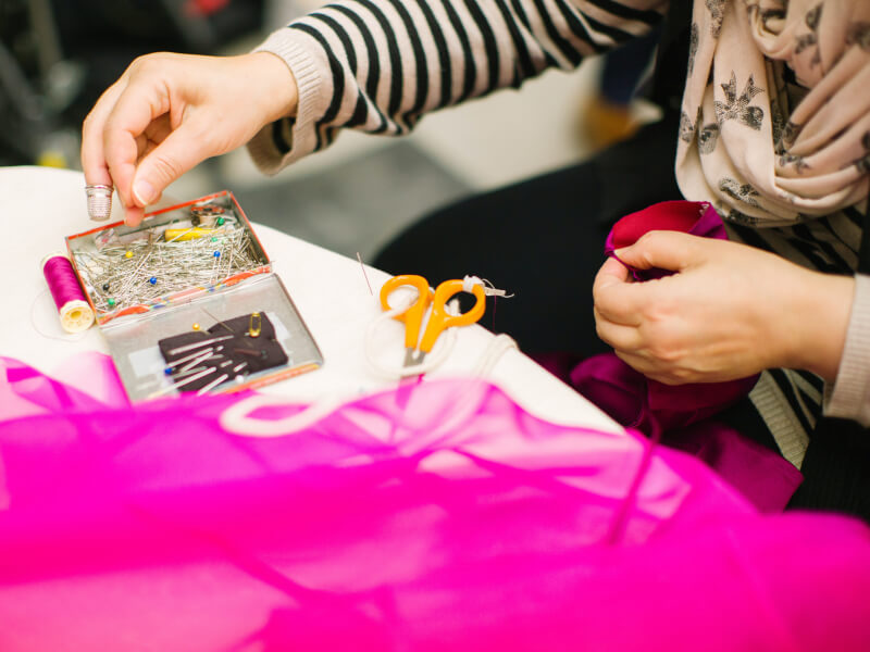 Woman sewing with pink net in the foreground